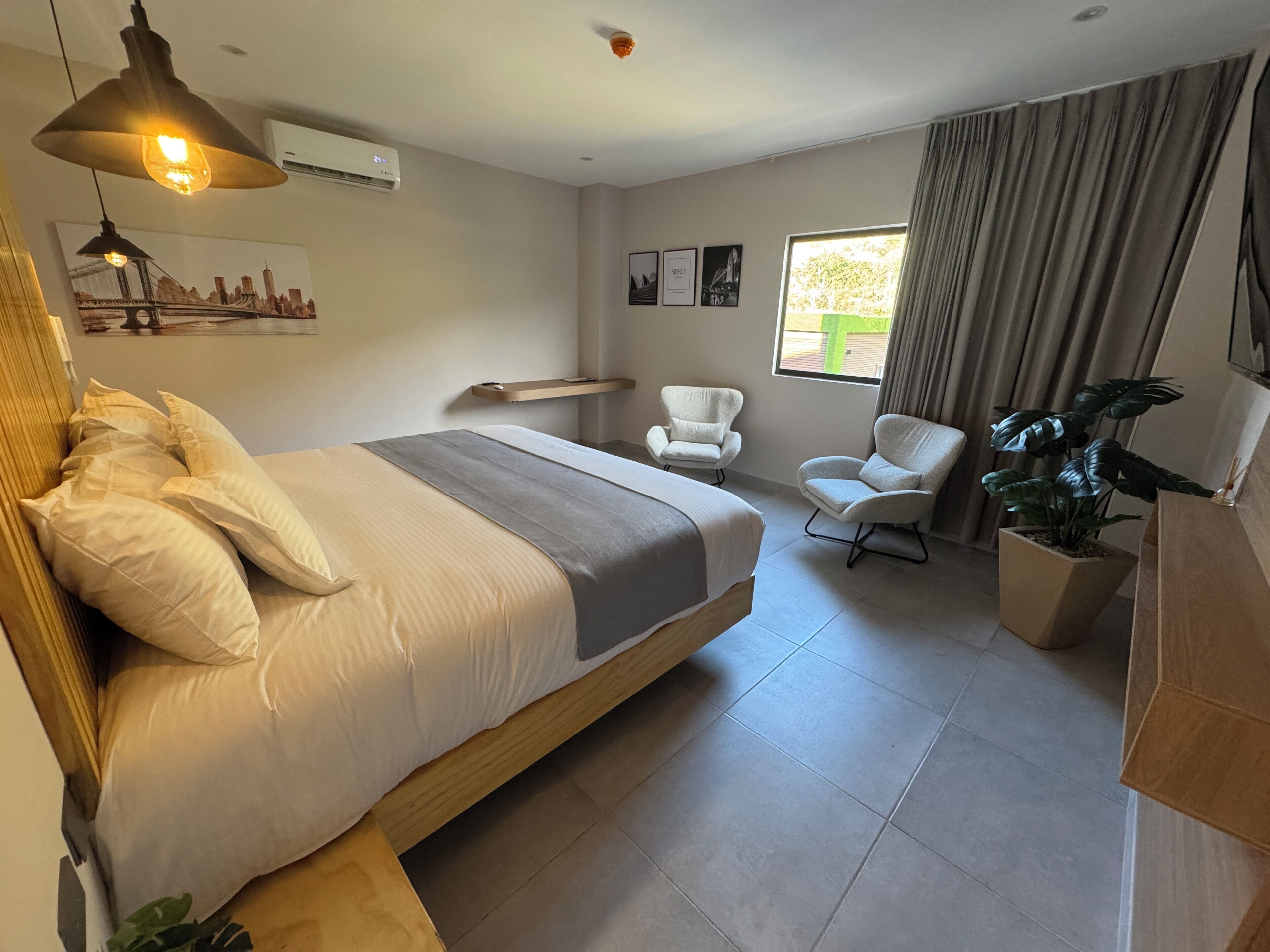 Une chambre d’hôtel moderne avec un grand lit, un bureau, une chaise et une plante en pot.