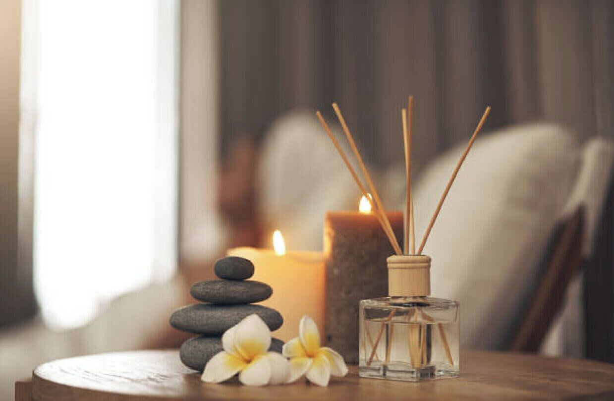 A candle, incense sticks, and flowers on a wooden table.