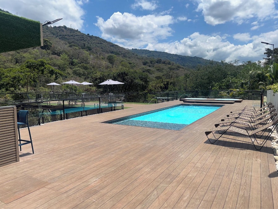Una piscina al aire libre, sombrillas, sillones reclinables de piscina