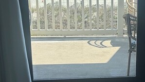 A room with a large window overlooking a beach, a white railing, and a chair. - Top floor Oceanfront Cherry Grove, North Myrtle Beach, SC 2 Bed 2 Bath Sleeps 7! (North Myrtle Beach)