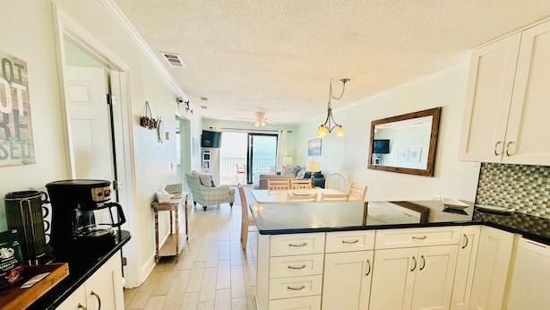 A kitchen with white cabinets, a central island, and a dining area with a view. - Top floor Oceanfront Cherry Grove, North Myrtle Beach, SC 2 Bed 2 Bath Sleeps 7! (North Myrtle Beach)