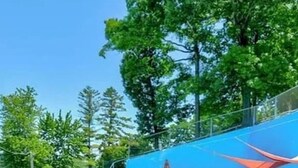 Una piscina con valla azul, tumbonas y un flotador amarillo.