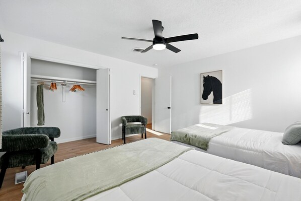 Un dormitorio con cama, una silla, un armario y un ventilador de techo.