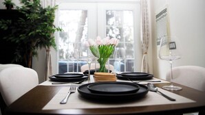A dining table set with black plates, a vase of pink flowers, and wine glasses. - Cozy Poconos A-Frame Cabin with Fire Pit, Pool, Lake (Tobyhanna)