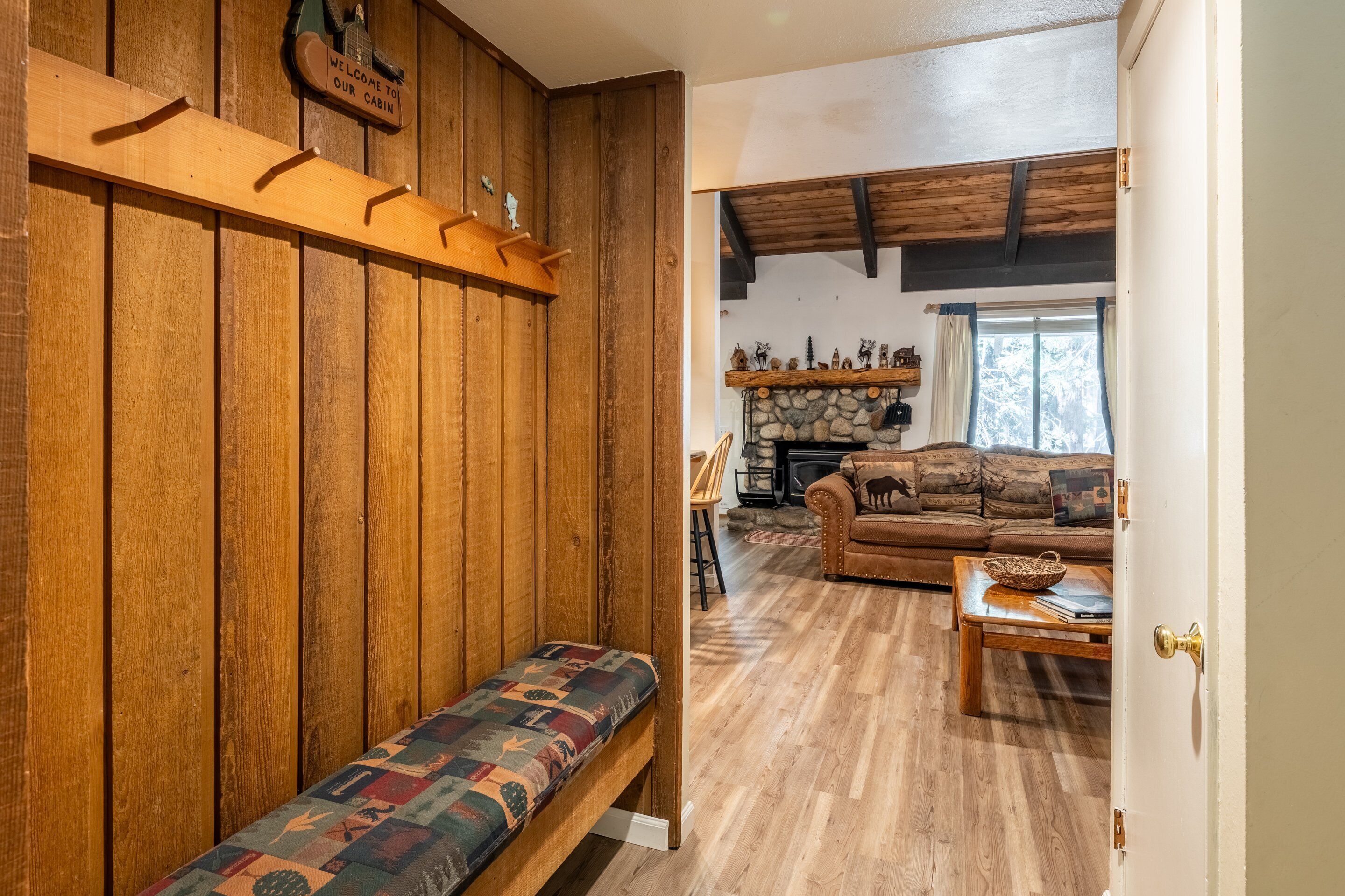 L’intérieur d’une cabane avec un banc en bois, un canapé et une cheminée.