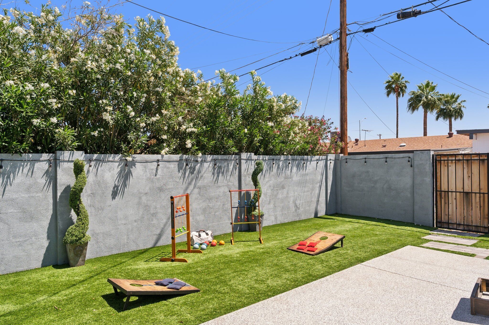 A backyard with artificial grass, a wooden swing set, a small table, and a garden wall.