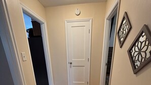 Un pasillo con suelo de madera, una puerta blanca y paneles decorativos en las paredes.