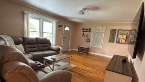 Una sala de estar con un sofá de cuero, una mesa de centro y un mueble para televisión.