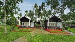 A bungalow-style accommodation with a central pathway, surrounded by lush greenery and palm trees. - Adhvasaha Beach Spa Resort (Port Blair)