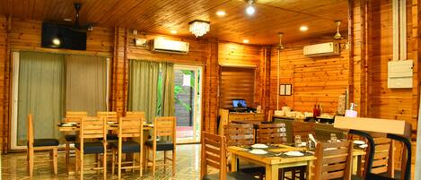 A wooden cabin with a dining area, kitchen, and a large window.