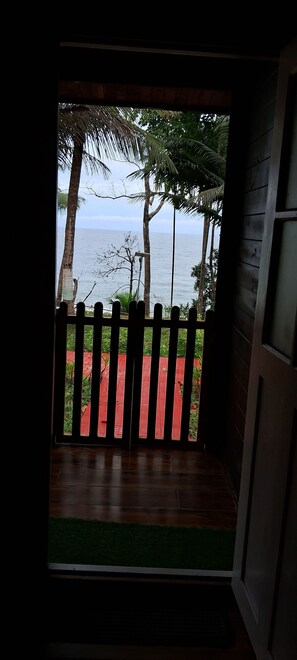A view from a room with a wooden floor and a red brick pathway leading outside.