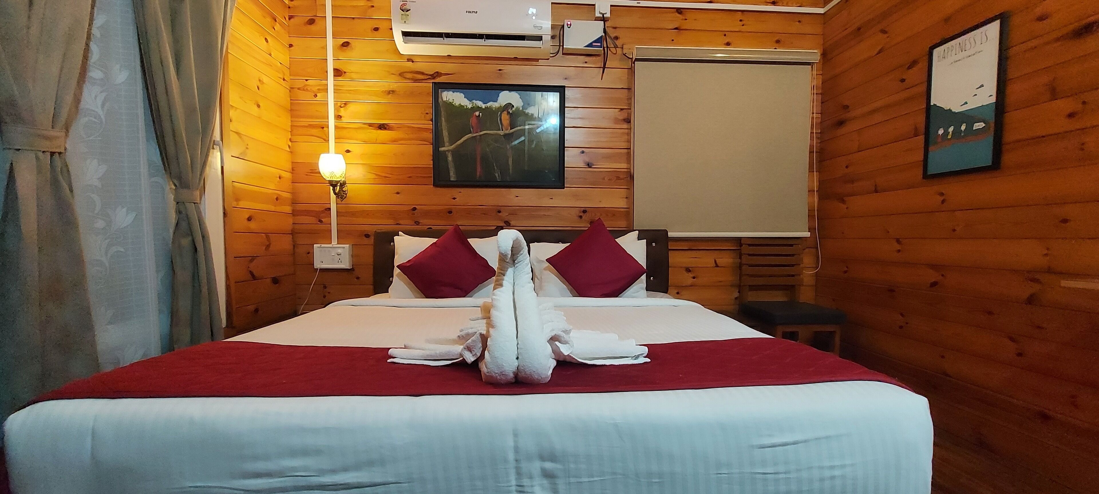 A wooden-paneled room with a bed, a painting, an air conditioning unit, and a projector screen.