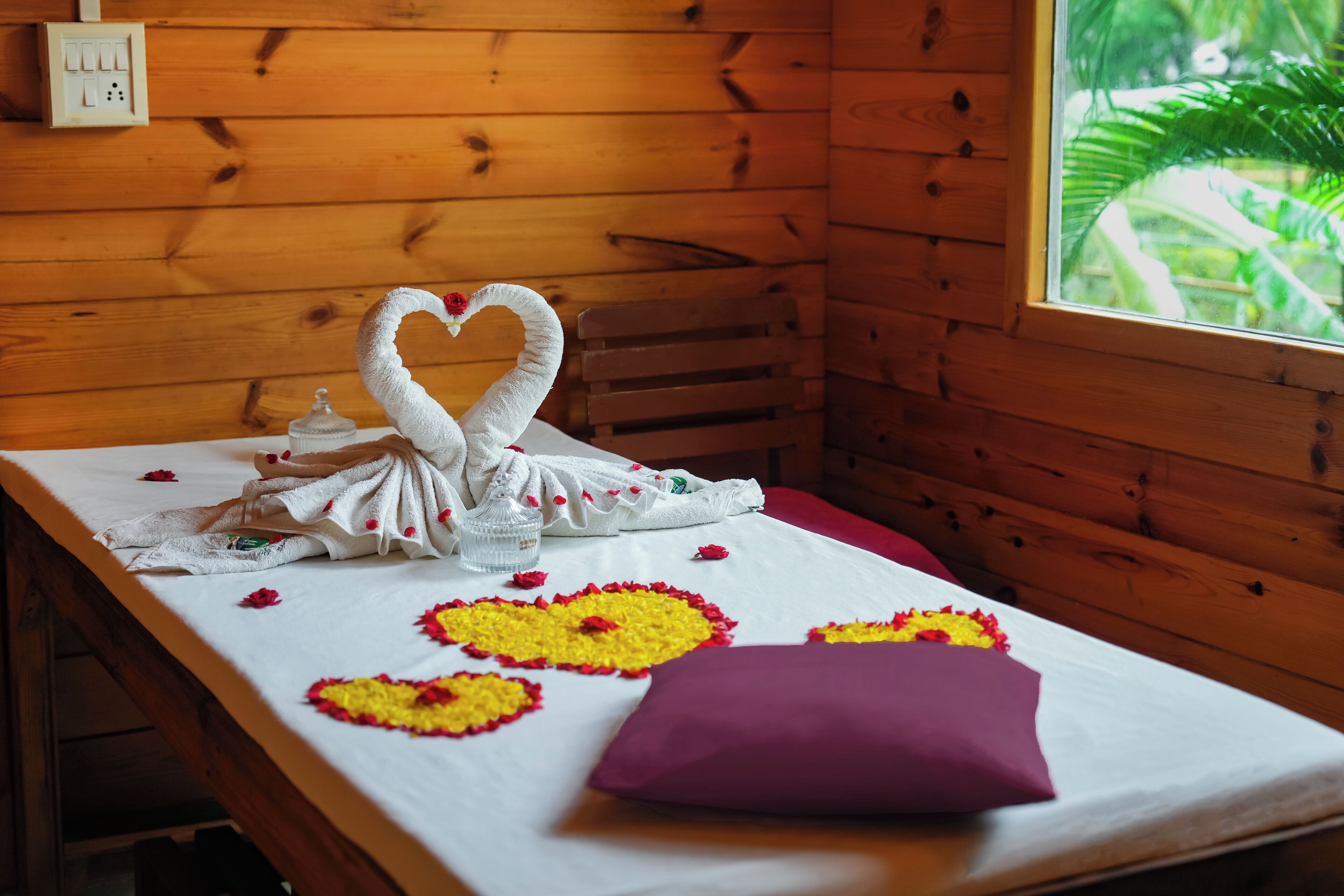 Habitación de cabaña de madera con cama, ventana con vista a follaje y enchufe de pared.