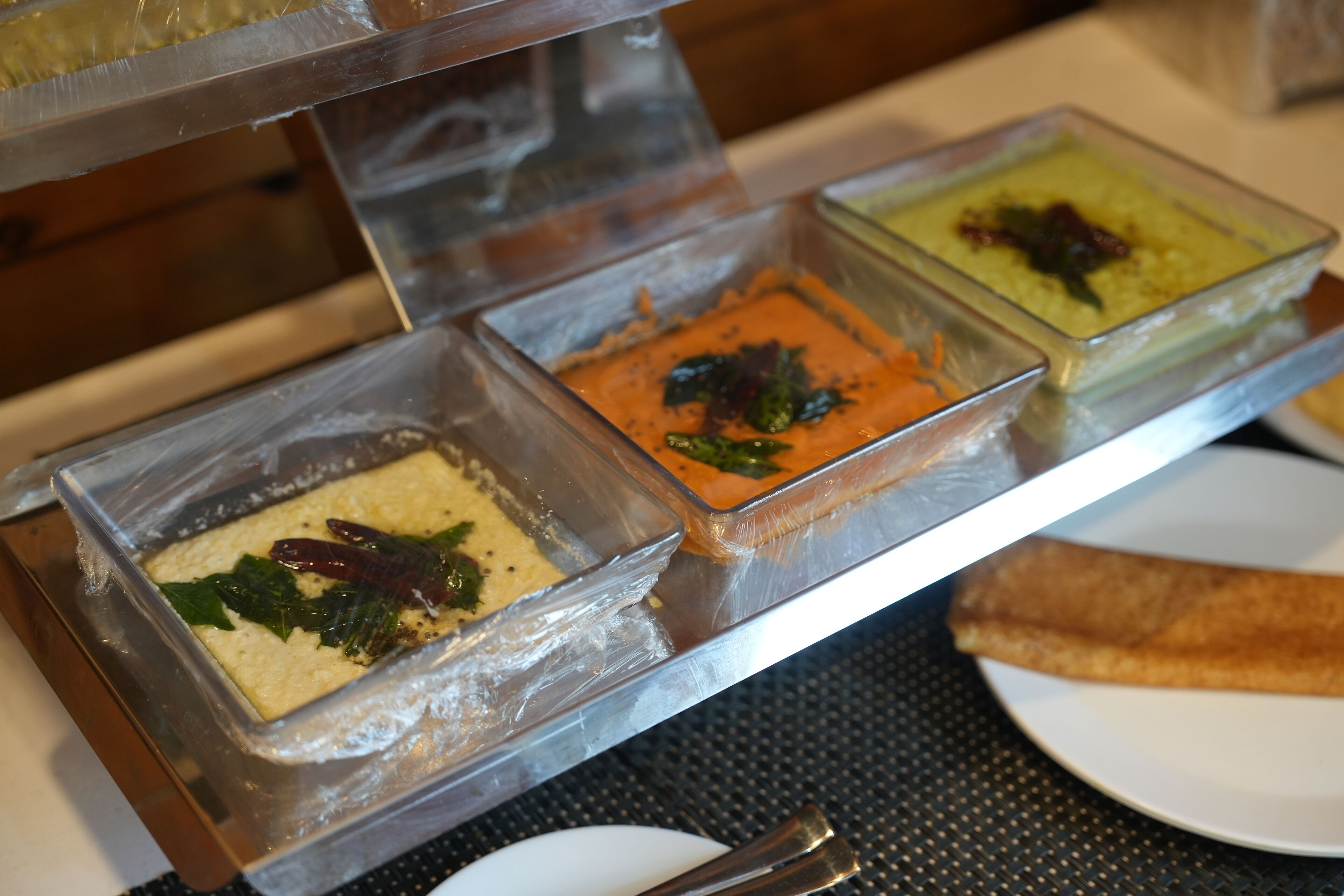 A buffet with various dishes in clear containers.
