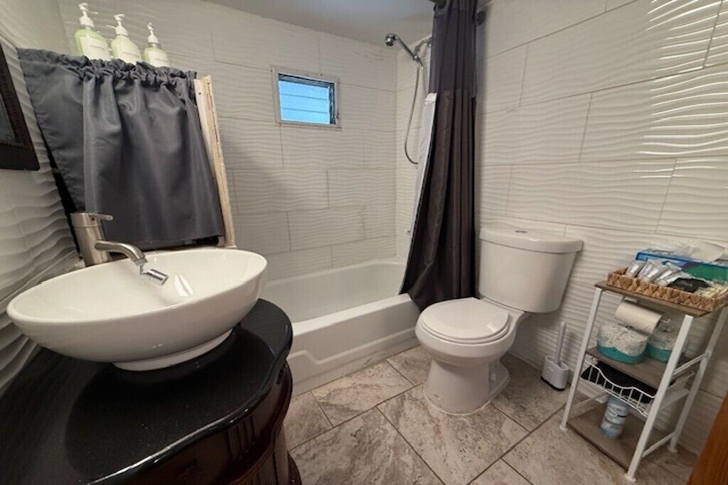 Een badkamer met een wastafel, toilet, bad en douchegordijn.