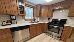 Een keuken met houten kastjes, roestvrijstalen apparatuur en een raam.