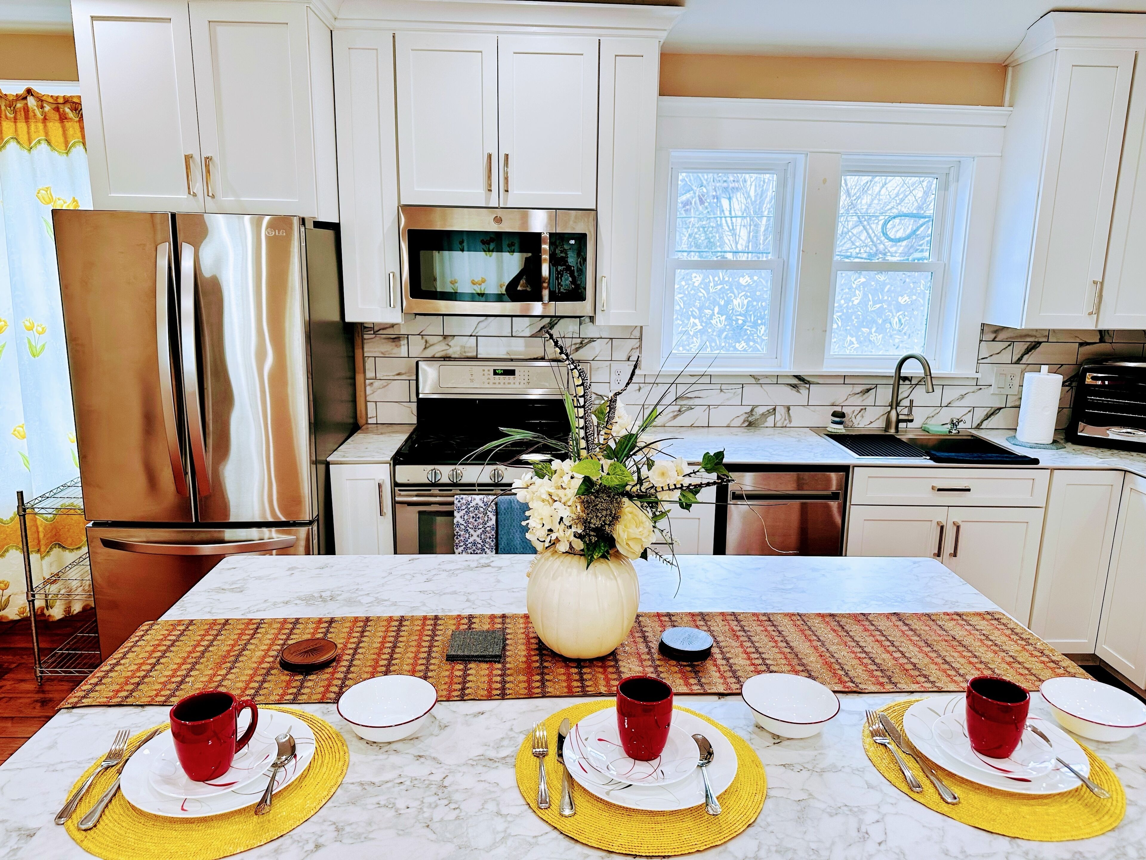 A modern kitchen with white cabinets, stainless steel appliances, and a dining area set for four.