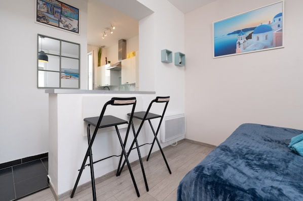 Une chambre moderne comprenant un lit, un bureau avec deux chaises, un miroir, un tableau et un radiateur.