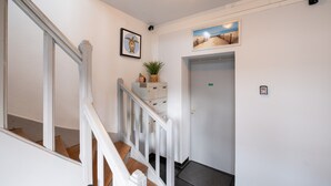 Eine Treppe mit weißen Geländern, eine Tür mit einem grünen Schild und ein gerahmtes Bild an der Wand.