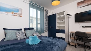 Ein Schlafzimmer mit Bett, Schreibtisch, Stuhl, Fernseher und Kleiderschrank.