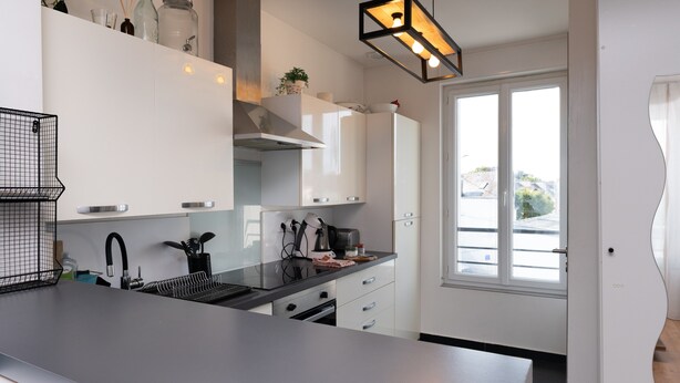 Eine moderne Küche mit weißen Schränken, einer schwarzen Arbeitsplatte und einem Fenster mit Blick.