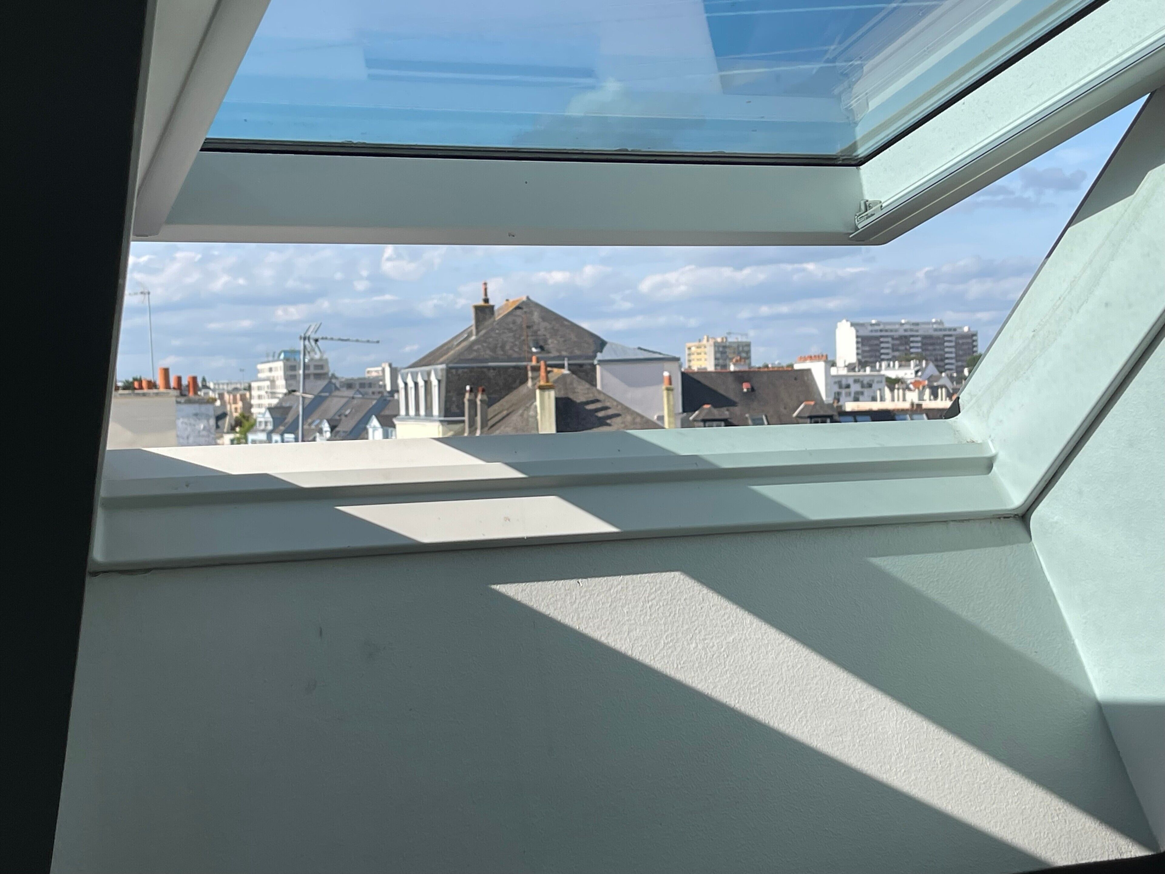 A skylight window with a view of a cityscape, including buildings and a crane.