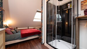 Ein Schlafzimmer mit Bett, Duschkabine, Fenster und Nachttisch.