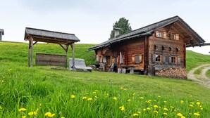 Una cabana de fusta amb teulada inclinada, un porxo de fusta i un cobert petit.