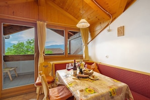 A wooden cabin with a dining table set for two, a window with curtains, and a view of greenery outside. - Apartment 'Lindenbaum' with Mountain View, Shared Terrace and Wi-Fi (Rodengo)
