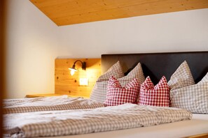 Un dormitorio con techo de madera, una cama con ropa de cama a cuadros y una lámpara fijada a la pared.