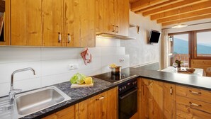 Une cuisine avec des meubles en bois, un évier en acier inoxydable, une cuisinière et une fenêtre donnant sur les montagnes.