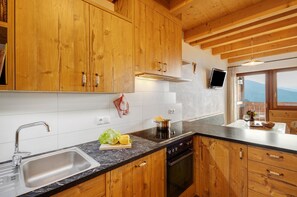 Une cuisine avec des meubles en bois, un évier en acier inoxydable, une cuisinière et une fenêtre donnant sur les montagnes.
