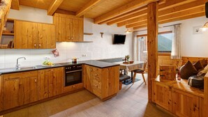 Une cuisine avec des meubles de rangement en bois, un évier et une cuisinière. On y trouve également un coin repas avec une table et des chaises.