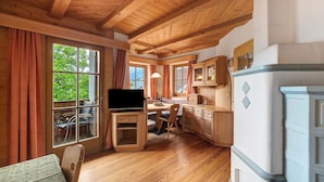 A wooden interior with a TV, dining table, chairs, and cabinets.