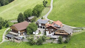 A rural property with multiple buildings, including a large barn and a house with solar panels.