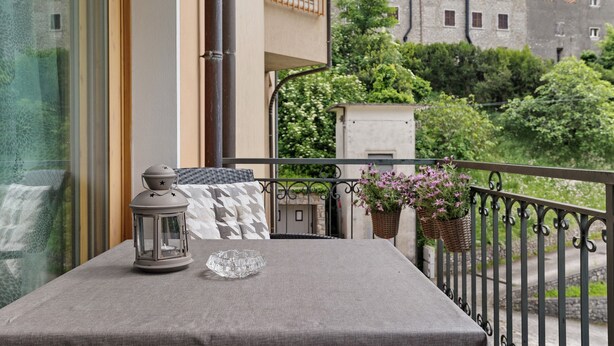 A balcony with a table, a lantern, and potted plants.
