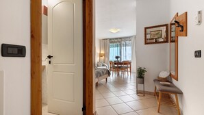 A hallway with a wooden door, a dining area with a table and chairs, a bench, and a potted plant.