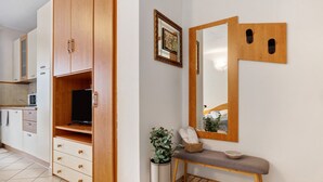A modern kitchen with cabinets, a television, a bench with a basket, and a mirror.