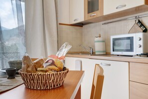 Eine Küche mit Mikrowelle, einem Brotkorb und einem Fenster mit Vorhängen.