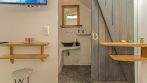 A bathroom with a wooden vanity, a sink, a mirror, and a television mounted on the wall. - Semi-basement 'Deluxe Suite' Room with Wi-Fi and Air Conditioning (Naxos)