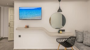 Une chambre moderne équipée d’une télévision, d’un miroir, d’un canapé et d’un fauteuil.
