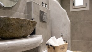 Une salle de bain avec un lavabo en pierre, des toilettes et un espace douche.