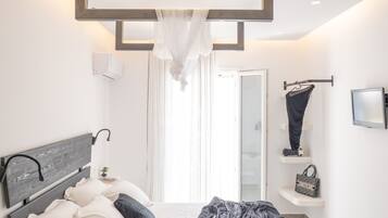 Een moderne slaapkamer met een bed, nachtkastje en een raam met gordijnen.