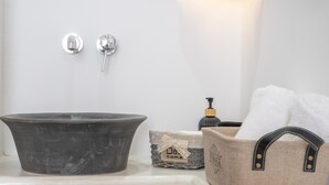 Un lavamanos con lavabo negro, un dispensador de jabón y una bolsa para guardar toallas.