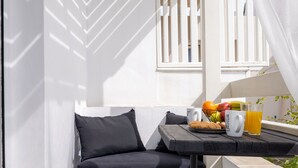 Un área de estar al aire libre con piso de piedra, una mesa con frutas, una taza y un vaso de jugo de naranja.