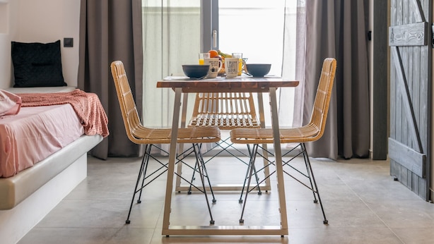 Una stanza accogliente con un letto, un tavolo con sedie e una finestra con tende.