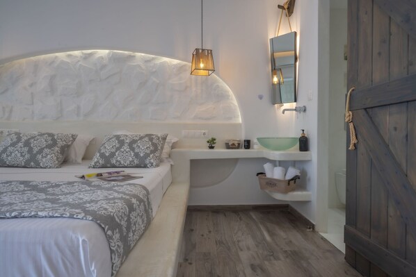 A bedroom with a bed, bedside table, and a wooden door.