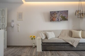 A modern living room with a sofa, a painting, and a vase with flowers.