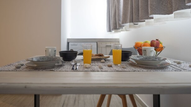 Ein Esstisch mit einer Schüssel, zwei Gläsern Orangensaft, einem Teller mit Früchten und einer Kaffeetasse.