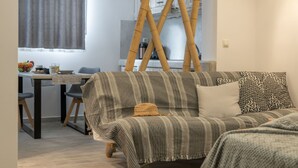 Ein modernes Wohnzimmer mit einem gestreiften Sofa, einem Essbereich mit Tisch und Stühlen sowie einer Küche mit Bambusmöbeln.